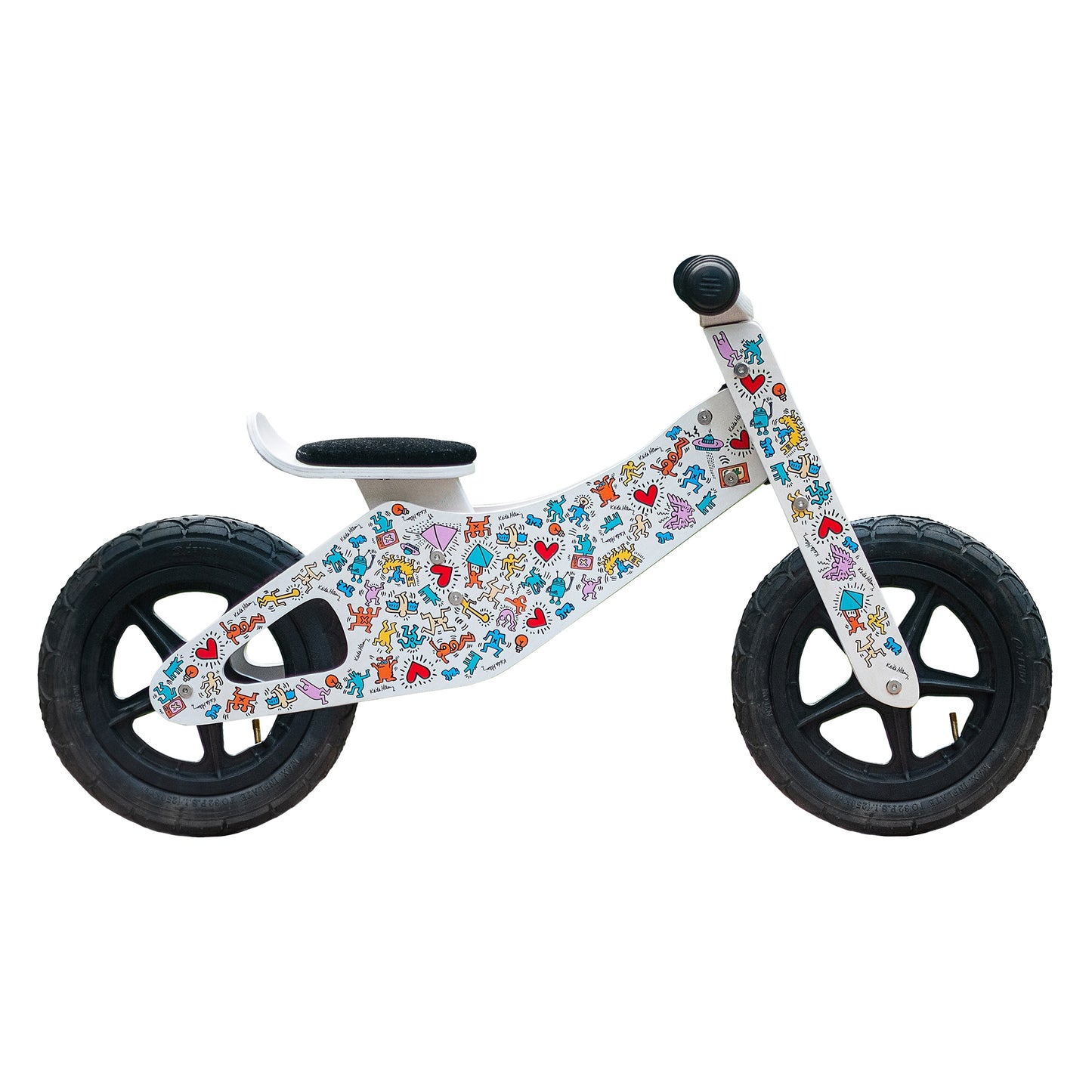 Children's balance bike with colorful Keith Haring graphics in front of a white background