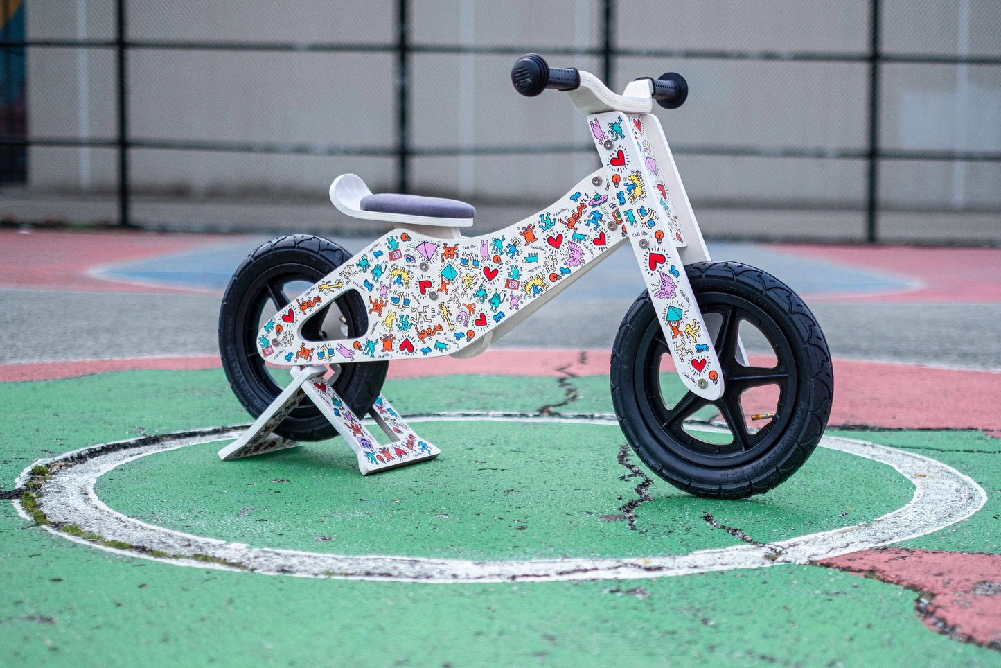 Keith Haring x Affinity balance bike with colorful graphics on playground surface