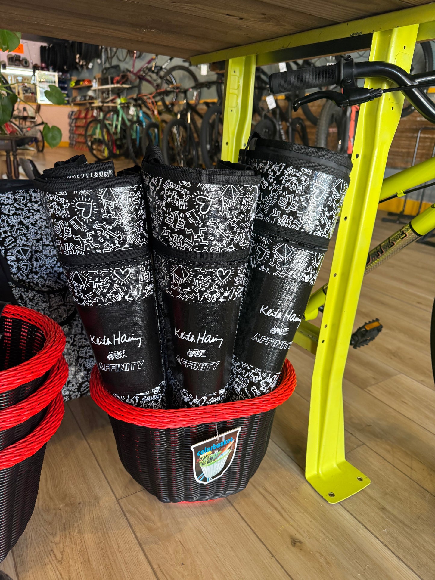 Keith Haring x Affinity XXL totes rolled up in a basket displayed in bike shop