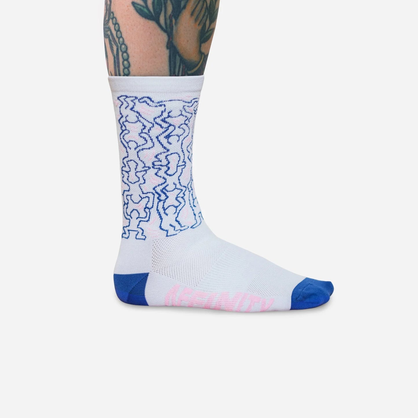 Cyclist wearing Affinity x Keith Haring “Dancing Figures” white and pink cycling socks with Haring’s iconic outlined characters, on white background.