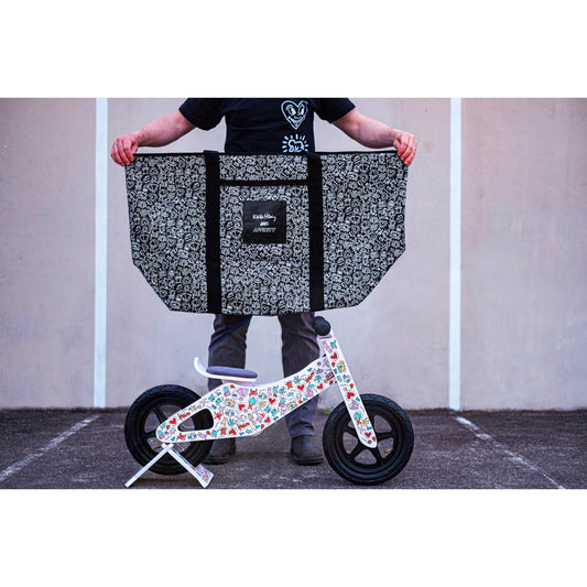 Person holding a Keith Haring x Affinity XXL Tote Bag with a small balance bike on the ground.